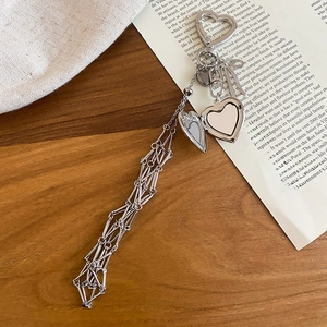 Detailed macro view of heart-shaped silver locket and tassel charm on a wooden surface