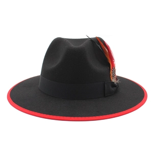 Detail of classic black wool fedora with red edge trim and colorful feather accent