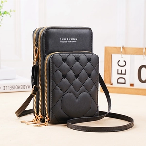 Detailed side view of black quilted heart crossbody bag with three zipper compartments