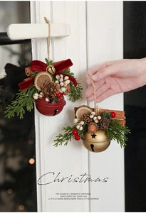 Detail of Christmas bell ornament with pine cone and bow on a white door handle
