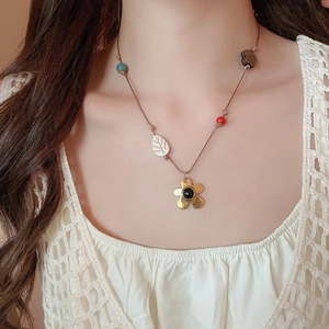 Détail du collier à fleurs avec pétales dorés, centre noir et perles multicolores