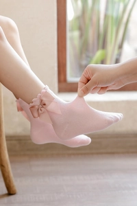 Detail showing elastic pink cotton sock with lace trim and satin bow decoration