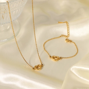 Detailed shot of gold knot heart necklace and bracelet set on soft satin fabric