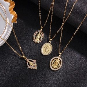 Close-up of four gold Virgin Mary pendants with colorful zircons on black background