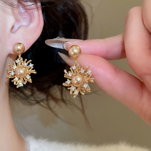 Vista macro degli orecchini a fiore placcati oro 18K con perla champagne e zircone