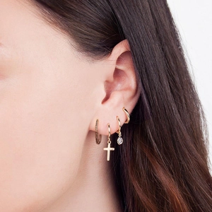 Detailed close-up of four gold hoop earrings with zircon and cross charms on ear