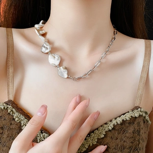 Collier en perles irrégulières et chaîne en argent porté par un mannequin au style chic