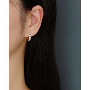 Close-up of geometric gold hoop earrings with black and white zircon stones on a model