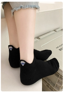 Detailed view of women's black low-cut sock featuring a blue diamond heel embroidery