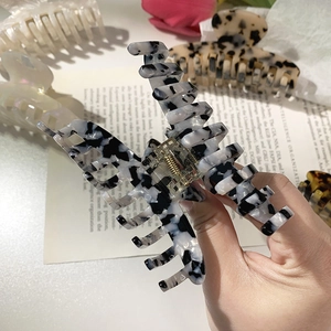 Detail shot of black and white marble pattern acetate hair claw clip held by hand