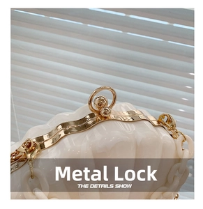 Detail shot of the golden hardware clasp and white acrylic shell bag with thick chain