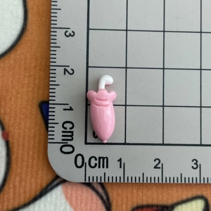 Vue détaillée d'une breloque aubergine rose sur une règle montrant la taille de 1cm