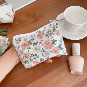 Detail of floral canvas pouch with pink flower patterns and zipper closure held in hand