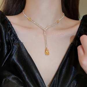 Gros plan sur le collier doré en Y avec cristaux et pendentif goutte d'eau jaune