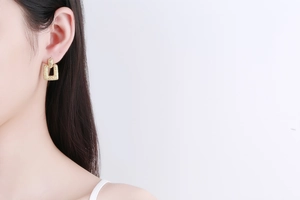 Detailed close-up of a minimalist 18K gold-plated earring with a frosted rectangular texture