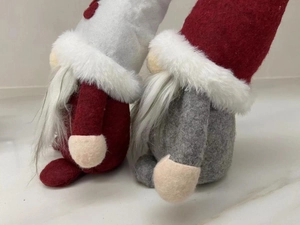 Close-up of handmade Christmas gnomes with felt hats and soft faux fur beards on marble