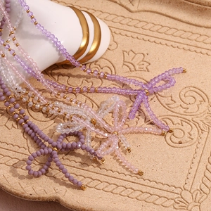 Detail of beaded necklace with light purple faceted crystal and golden bow pendant