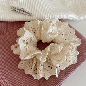 Detailed shot of white lace embroidered scrunchie with colorful gem silver hair clip