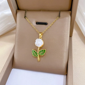 Detail of a luxury rose pendant necklace with white flower petals and green leaf accents