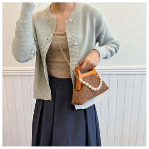 Detail of tweed evening bag featuring a vintage wooden handle and elegant pearl chain