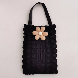 Close-up of black popcorn fabric handbag with a large 3D white flower decoration