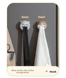 Adhesive bear-shaped push-in towel holder storing an apron and towel on a fridge