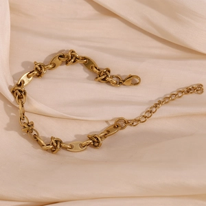 Detail of 14K gold plated coffee bean knot chain bracelet on champagne silk fabric