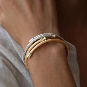 Detailed macro view of silver and gold twisted cable cuff bracelets in a layered style