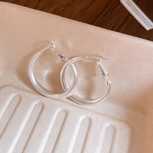 Close-up of silver hoop earrings with brushed metal texture and 925 silver needles
