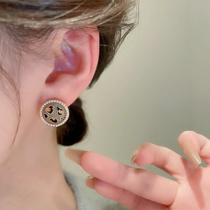 Close-up of a vintage round pearl earring with leopard enamel on model's ear