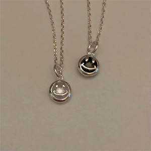Close-up of minimalist sterling silver smiley face pendants with black and white zircon