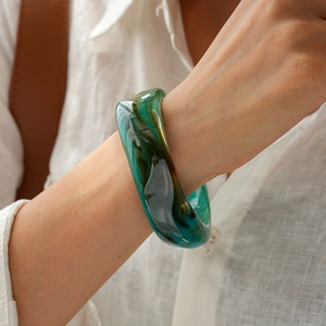 Detail of chunky acrylic marble bangle in green and amber on model wrist
