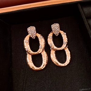 Detail of hammered gold earrings with cubic zirconia inlay on a black velvet background