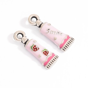 Detailed macro of pink enamel strawberry charm and silver Smile bead for DIY jewelry