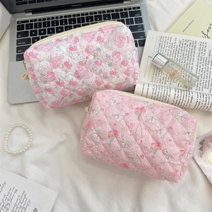 Detailed close-up of quilted floral cosmetic bags with cute rabbit patterns on a desk