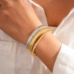 Detailed close-up of 18k gold plated cuff bracelets with intricate woven metal textures