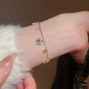 Detail of gold chain bracelet with sparkling bow charm and clear crystal accents