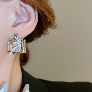 Macro shot of a rectangular zircon earring with vintage hollowed silver metal texture