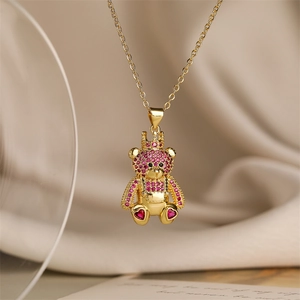 Macro shot of gold crown bear pendant necklace with pink rhinestones on a beige fabric