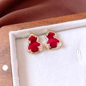 Macro detail of red flocked gourd earrings with gold edges and tiny star accents