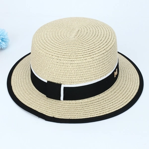 Gros plan détaillé d'un chapeau de paille avec ruban noir et accessoire doré en M