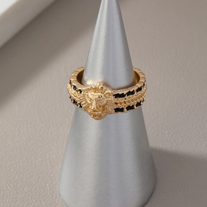 Vintage lion head ring in gold and black enamel displayed on a conical stand