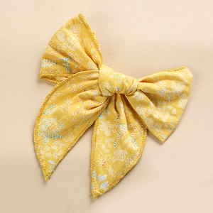 Detail of yellow cotton bow hair clip featuring delicate blue and white floral patterns