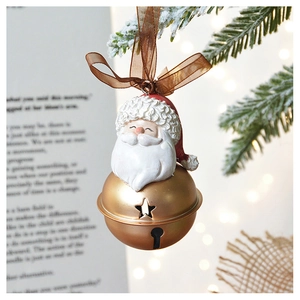 Golden Santa bell ornament with star cutouts hanging on snowy Christmas tree branch