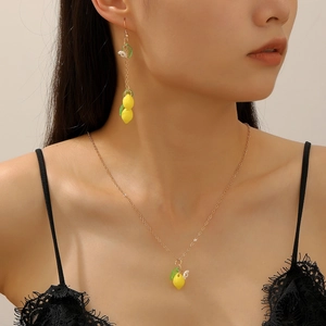 Detail shot of lemon necklace and long earrings with green leaves on model wearing black lace
