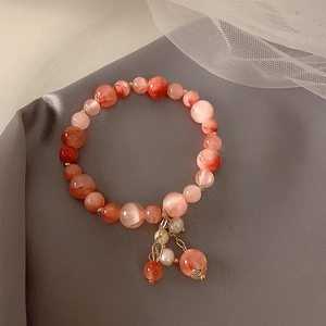 Minimalist white crystal bracelet with pink beads and gold accents on silky background