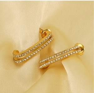 Detail view of gold double-layer safety pin earrings with sparkling white crystals