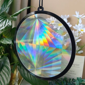 Close-up of a black circular suncatcher prism pendant creating colorful rainbow light effects