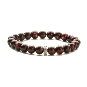 Macro detail of polished dark red garnet beads and engraved silver metal spacer bead