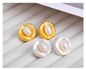 Detail of irregular gold and silver baroque pearl earrings in a white jewelry box